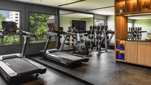Academia moderna com esteiras, máquinas de peso e um espaço de bar.