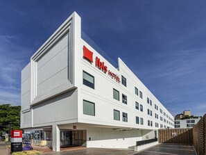 Un hotel moderno con un llamativo logotipo rojo, entrada de cristal y fachada de ladrillo.