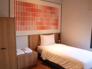 Ein Hotelzimmer mit einem Bett, einem Holzschrank und einem großen, abstrakten Gemälde an der Wand.