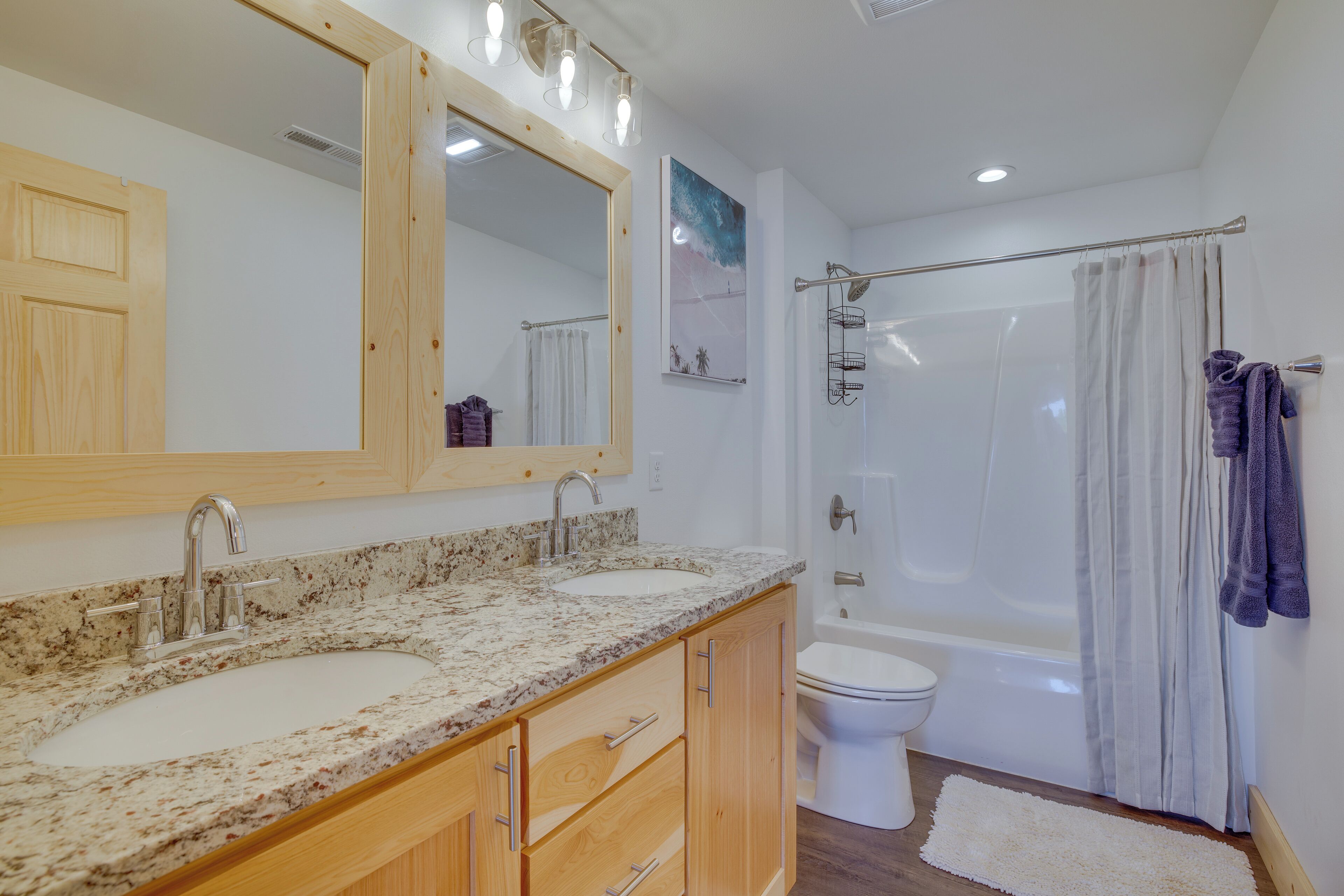 A bathroom with two sinks, a mirror, a toilet, and a bathtub.