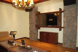 A living room with a stone wall, a flat-screen TV mounted above a wooden cabinet, and a chandelier. - Yongtai Gening Ant Nest Egg Homestay (Yongtai)