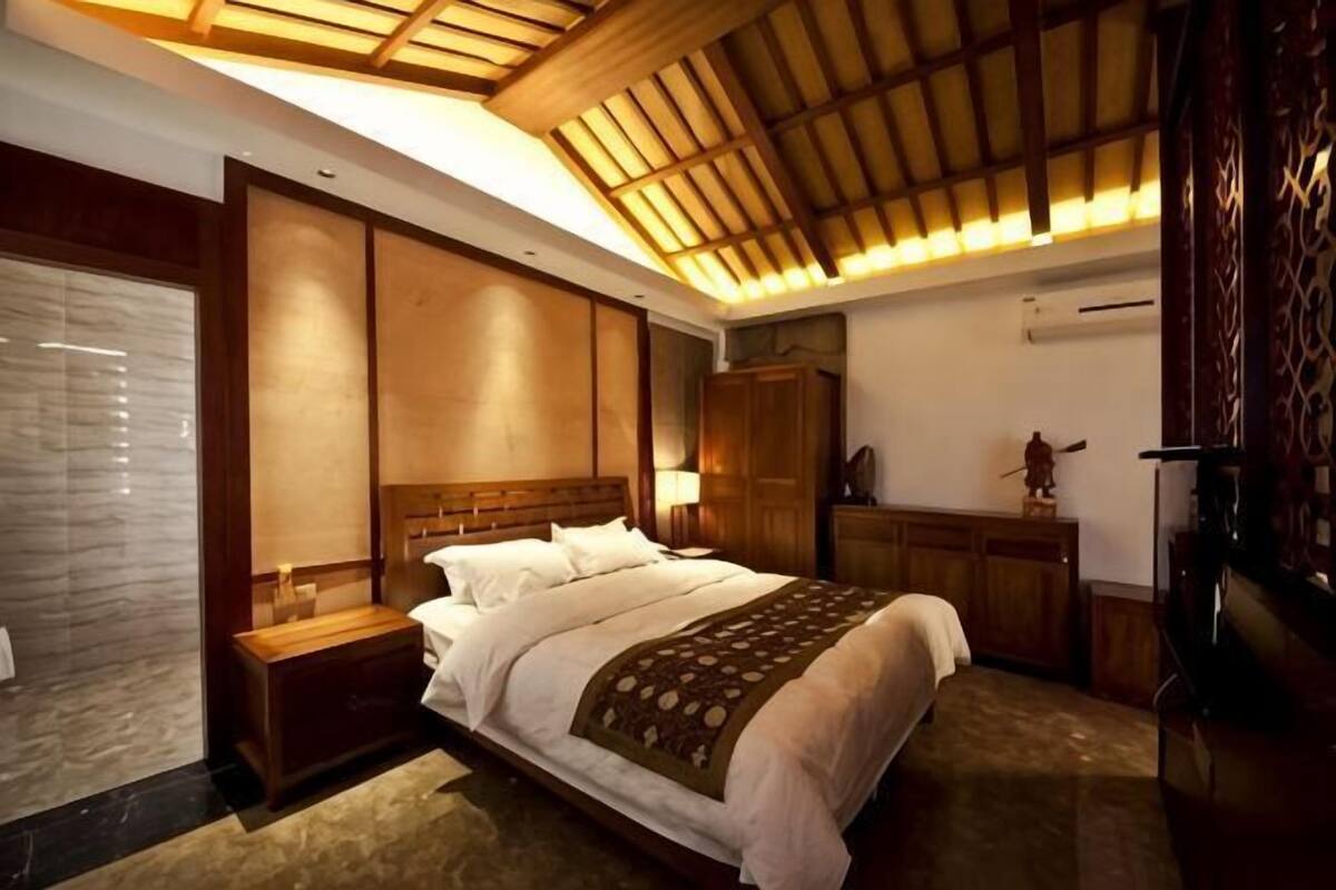A bedroom with a large bed, wooden headboard, bedside tables, a wardrobe, and a ceiling with wooden slats.