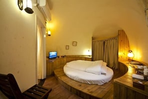 Ein gemütliches Zimmer mit einem bogenförmigen Holzbett, einem kleinen Schreibtisch mit einem Computer und einer Holzbank.