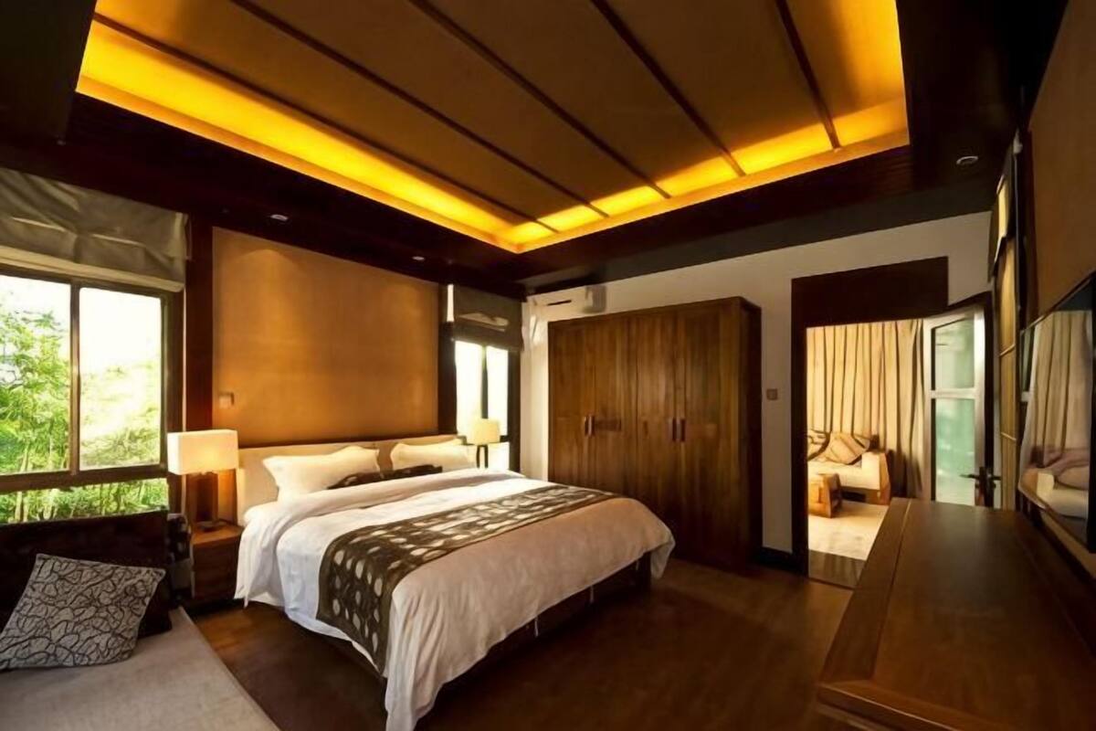A bedroom with a large bed, a nightstand, a wardrobe, and a desk.