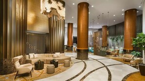 Un vestíbulo moderno con una zona de estar central, amplias columnas decorativas y una alfombra estampada.