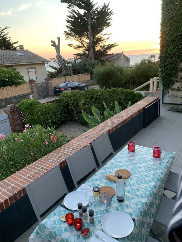 Een terras met een tafel gedekt voor twee personen, omringd door groen en een bakstenen muur.