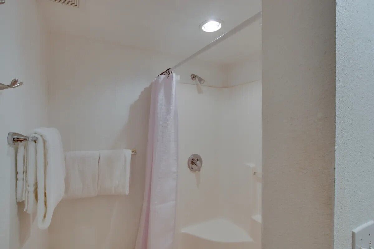 A bathroom with a shower, a towel rack, and a ceiling light.
