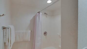 A bathroom with a shower, a towel rack, and a ceiling light.