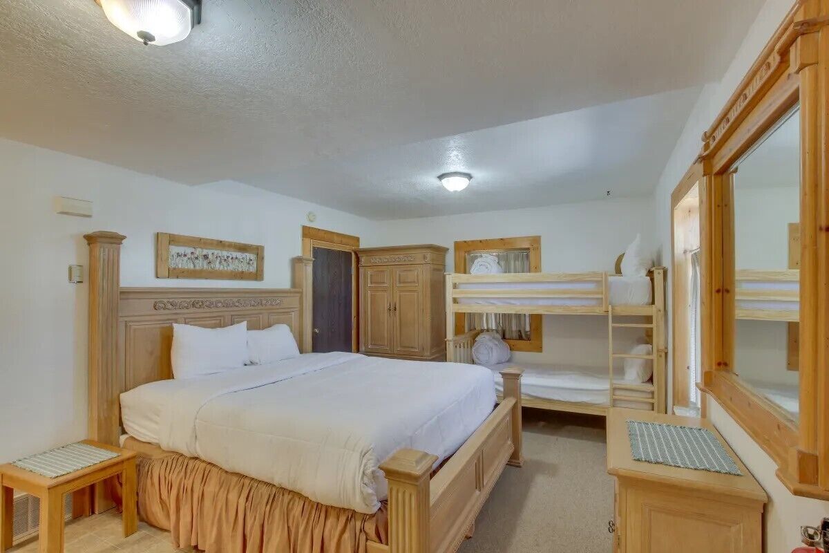 Une chambre à coucher avec un grand lit, une armoire en bois, un miroir et un lit superposé.