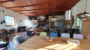 A spacious dining area with a large wooden table, multiple chairs, and hanging pendant lights.