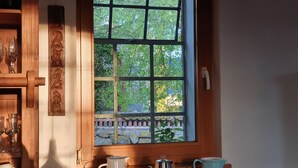 A kitchen with a window, a coffee maker, and a mug on the counter.