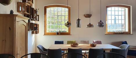 A dining area with a wooden table, black chairs, and pendant lights.