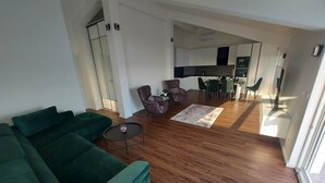 A spacious living area with a green sofa, a small round table, and a dining area with chairs and a table. - Apartment in Lokva Rogoznica with Seaview, Terrace, Air condition, WIFI (5118-1) (Lokva Rogoznica)