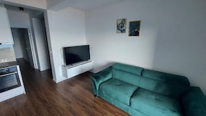 A living room with a green sofa, a flat-screen TV, and a white entertainment unit. - Apartment in Lokva Rogoznica with Seaview, Balcony, Air condition, WIFI (5118-5) (Lokva Rogoznica)