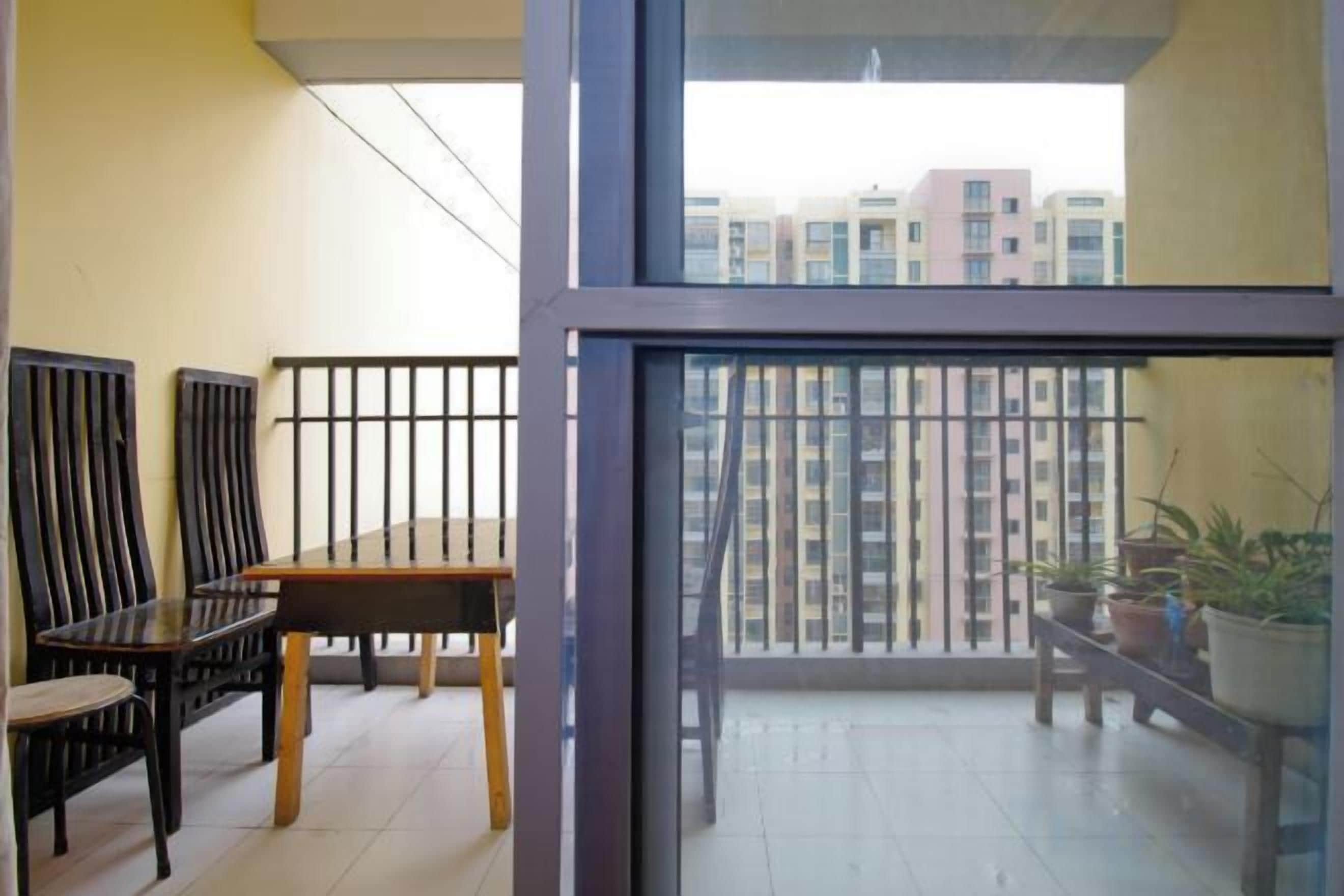 Un balcon avec une table et des chaises, des plantes en pot et une vue sur les immeubles de grande hauteur.