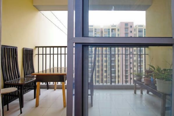 A balcony with a table and chairs, potted plants, and a view of high-rise buildings. - Makerhouse Hostel (Hefei)