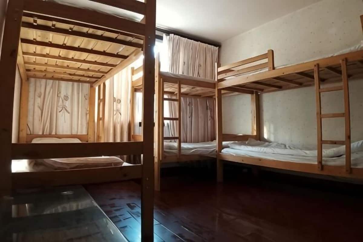 Ein Zimmer mit Etagenbetten, Holzboden und Vorhängen.