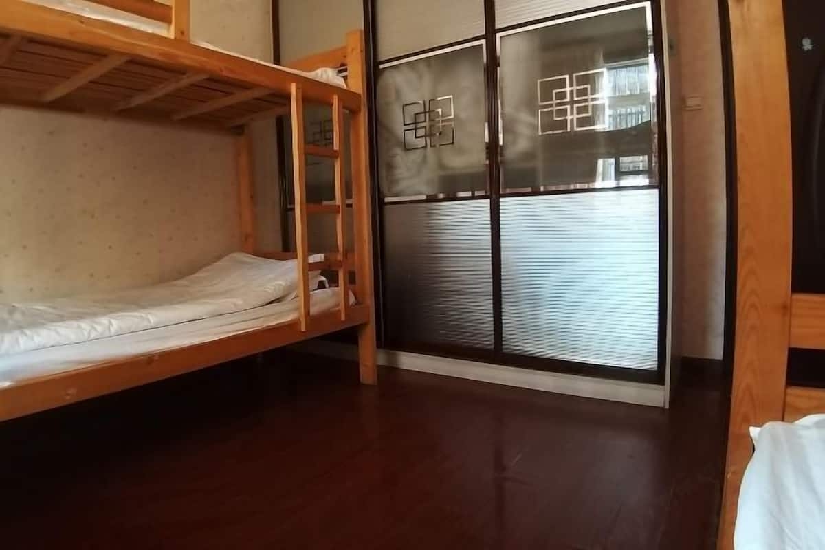 Ein Zimmer mit Etagenbett, einer Schiebetür mit geometrischem Muster und Holzboden.