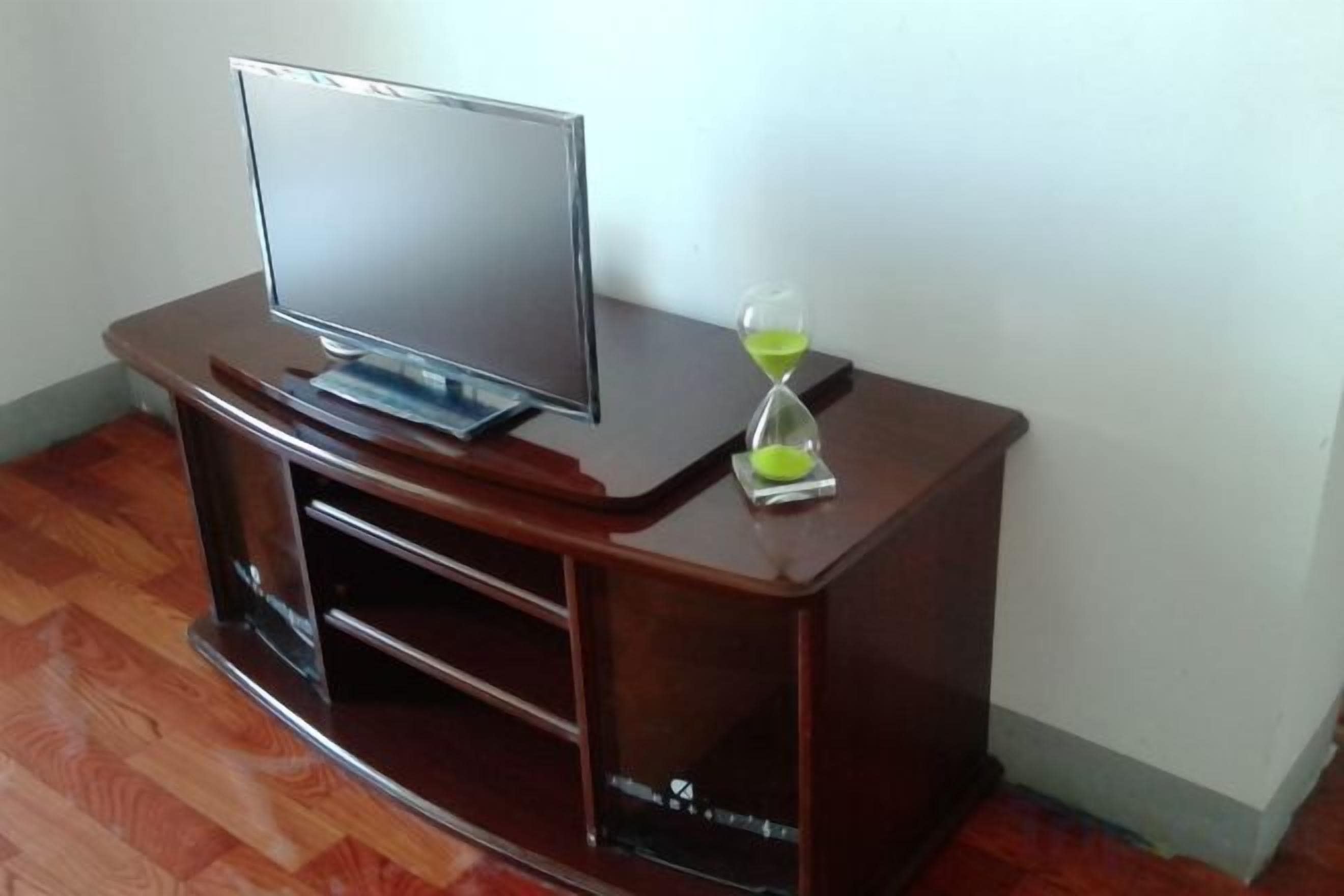Un mueble de madera con un centro de entretenimiento, un televisor de pantalla plana y una hora de arena.