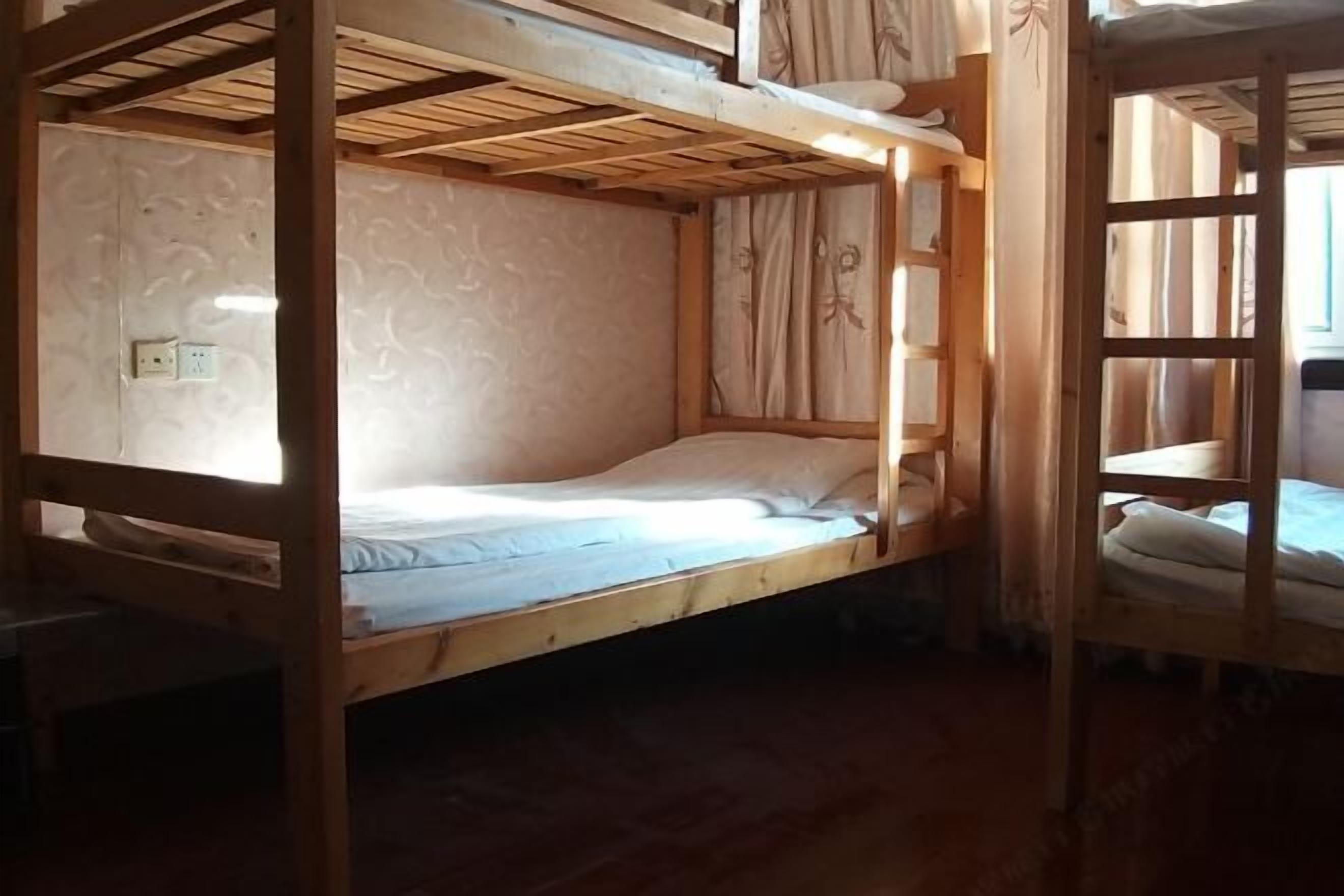A wooden bunk bed room with a window, curtains, and a visible electrical outlet.