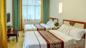 Habitación de hotel con dos camas, televisor, escritorio y ventana con cortinas.