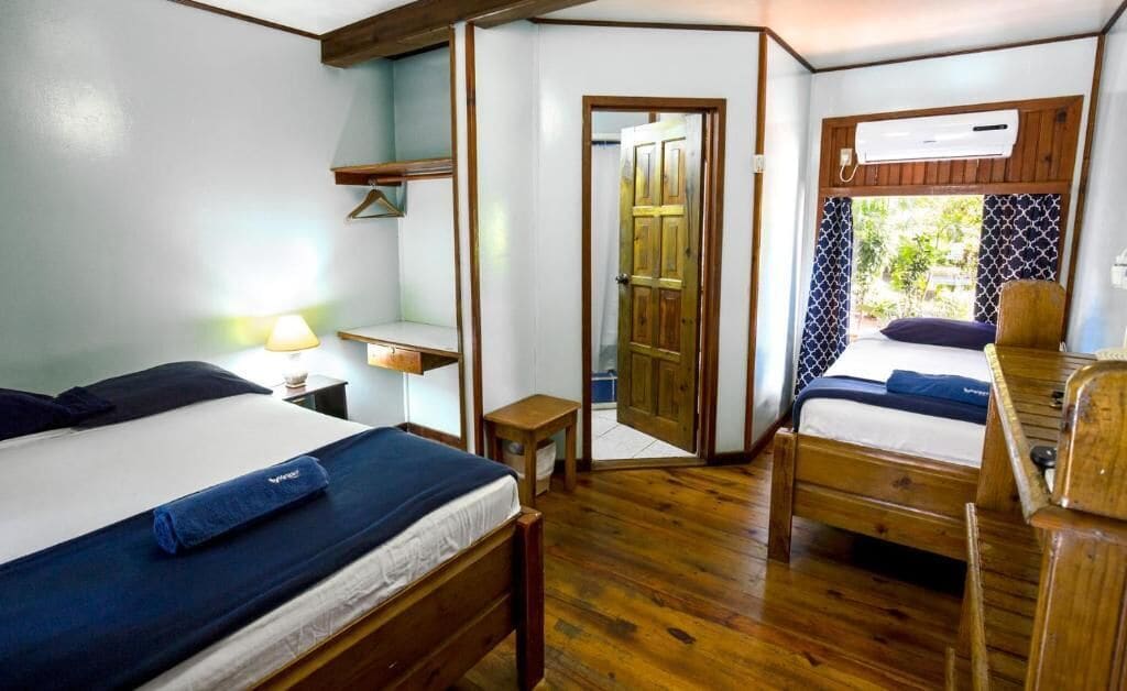 Una habitación pequeña con dos camas de madera, una mesita y una silla.