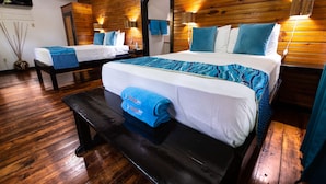 A wooden-paneled room with two beds, a bench, and a mirror. - Mango Inn Resort  (Isla de Utila)