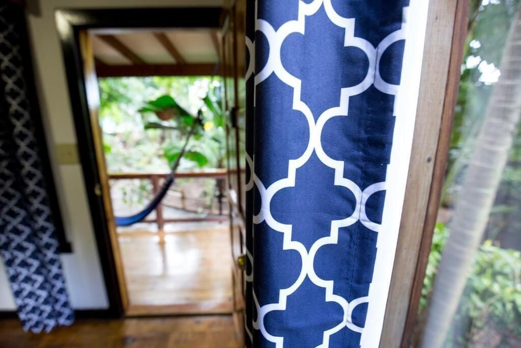 A doorway leading to a wooden deck with a hammock.