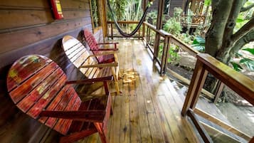 Una terraza de madera con una hamaca, sillas de madera y un extintor.