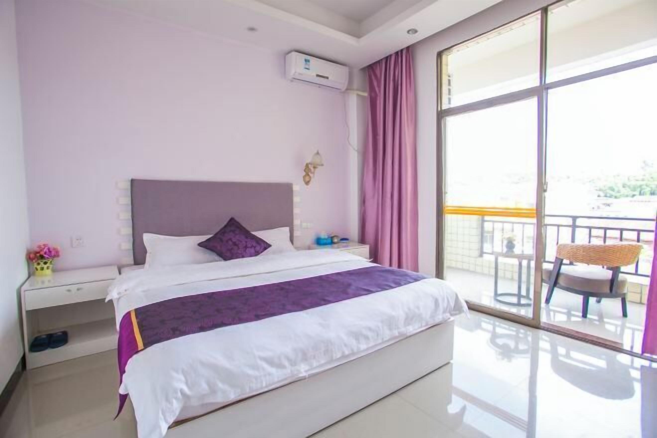A hotel room with a bed, a nightstand, a window with curtains, and a view of the outside balcony.