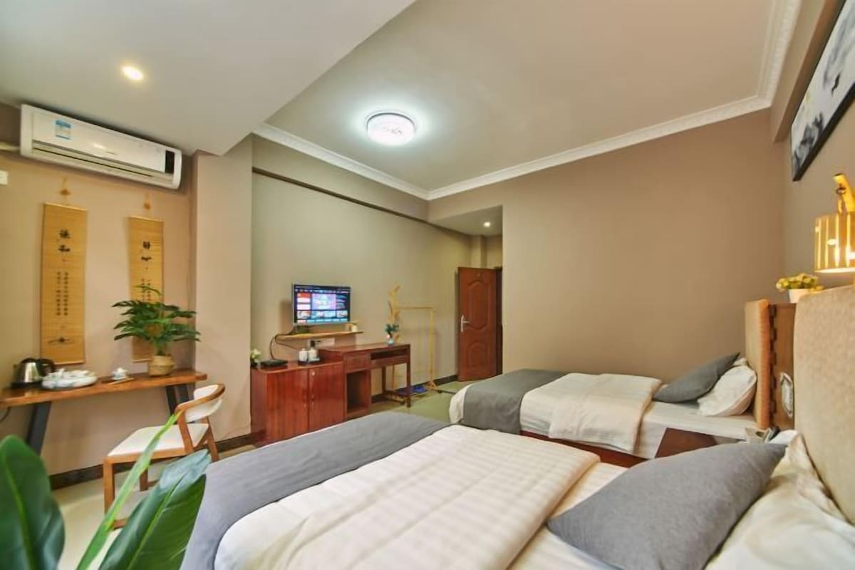A hotel room with two beds, a desk with a computer, an air conditioner, and a television.