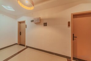 Un pasillo con una puerta a la izquierda, una puerta a la derecha y un equipo de aire acondicionado instalado en la pared.