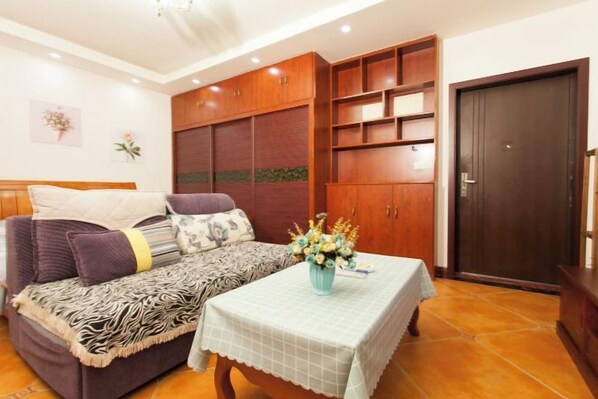 A room with a sofa, a table with a tablecloth, a cabinet, and a door.