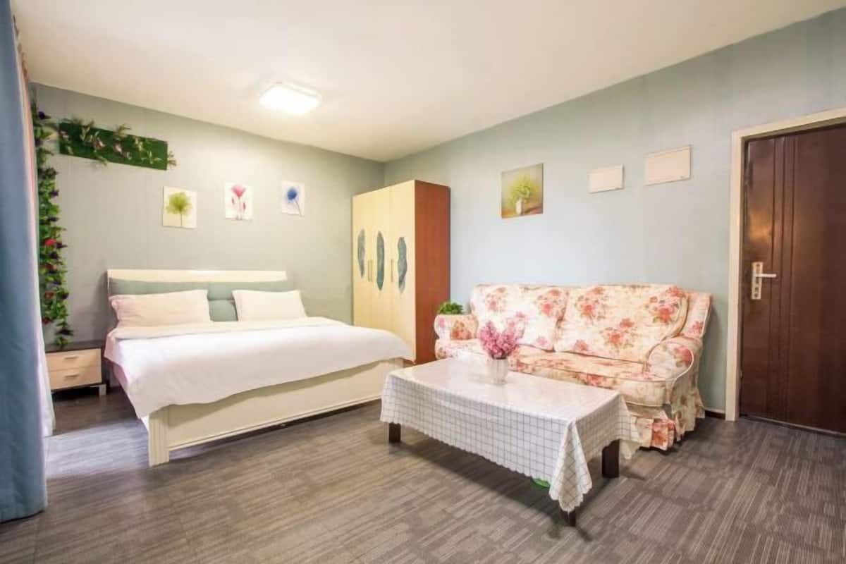 Ein Schlafzimmer mit einem Bett, einem blumigen Sofa, einem Couchtisch und einem Kleiderschrank.