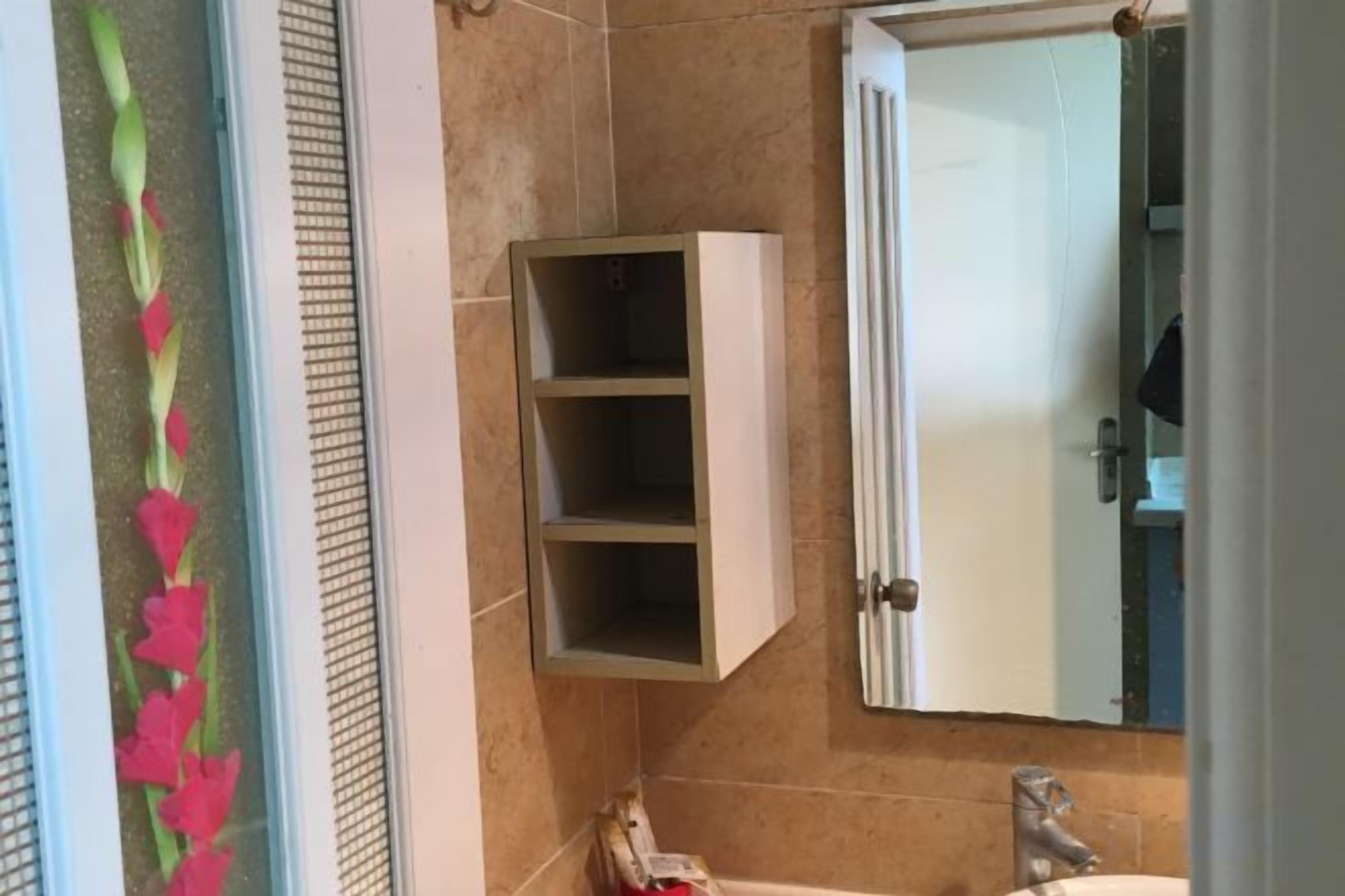 A bathroom with a white cabinet, a mirror, and a towel rack.