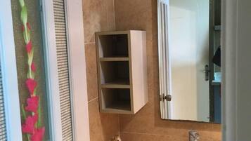 A bathroom with a white cabinet, a mirror, and a towel rack.