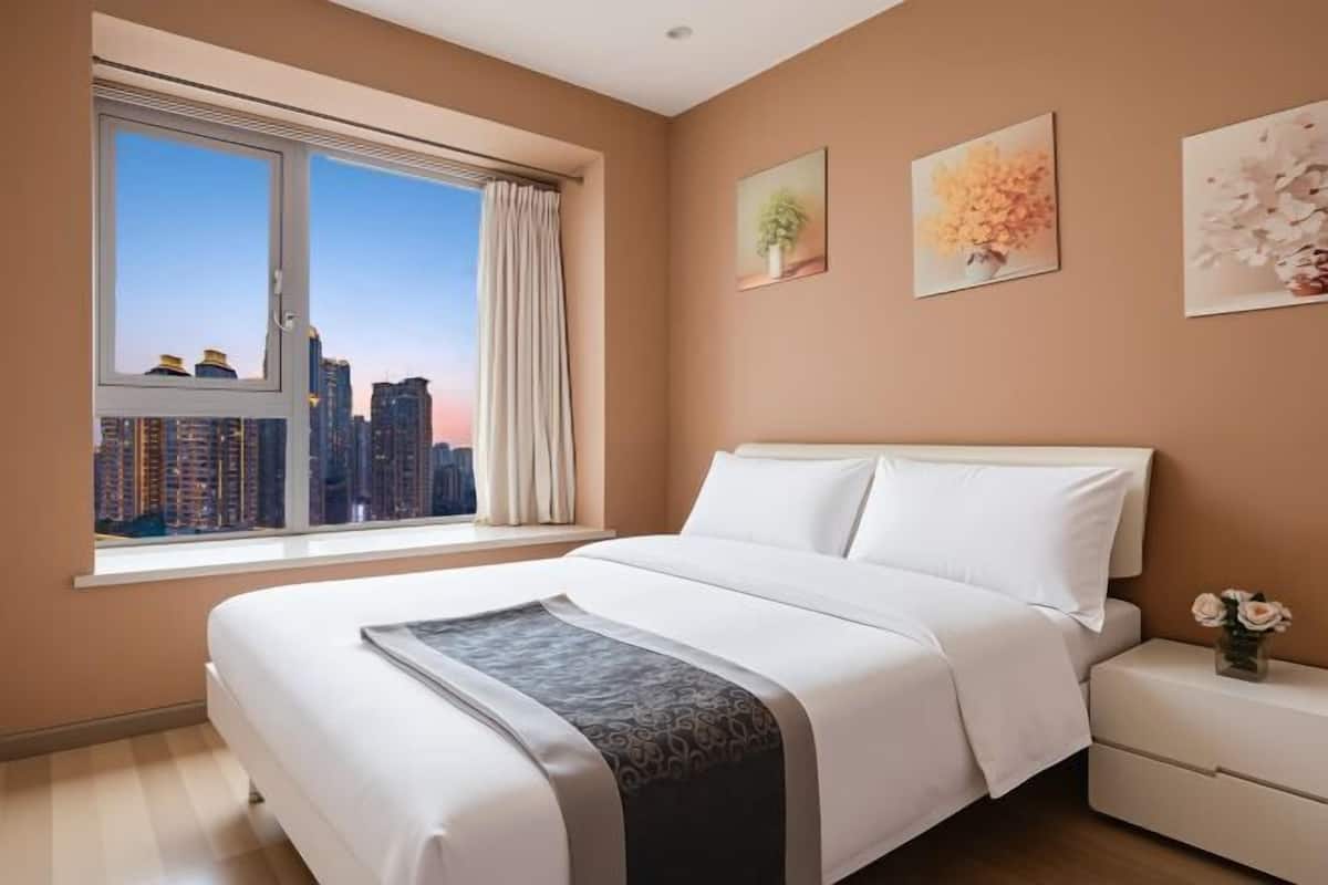 Ein Schlafzimmer mit großem Fenster, einem Bett, einem Nachttisch und Wandbildern.