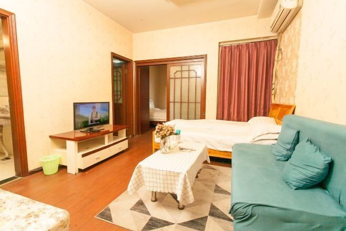 A hotel room with a bed, a sofa, a television, and a small table with a vase.