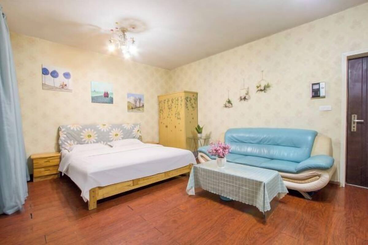 Ein Schlafzimmer mit einem Bett, einem blauen Sofa, einem kleinen Tisch mit einer Vase und einem Kleiderschrank.