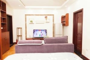 Ein Hotelzimmer mit Bett, Fernseher, Kleiderschrank und Tür.