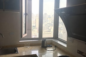 A kitchen with a window, a kettle, and a sink.