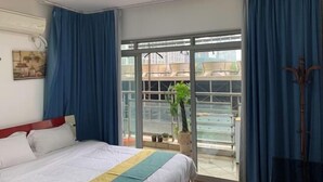 Ein Hotelzimmer mit Bett, Fenster und Balkon mit Pflanze.