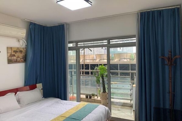 A hotel room with a bed, a window, and a balcony with a plant. - Chongqing Ruika Apartment (Guanyinqiao Pedestrian Street) (Chongqing)