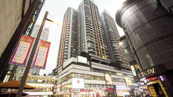 A high-rise building with multiple floors, a commercial area with shops, and a KTV sign.