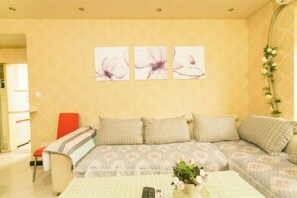 Ein Wohnzimmer mit einer Couch, einem Tisch mit Blumen und Wandbildern.
