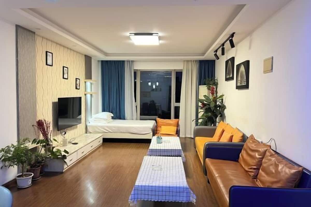 Ein modernes Wohnzimmer mit Sofa, Bett, Fernseher und Couchtisch.
