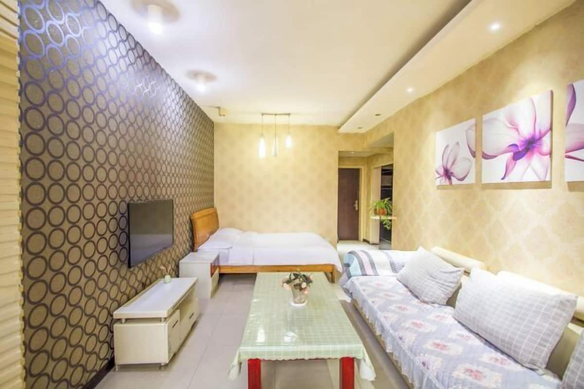 Ein Schlafzimmer mit einem Bett, einer Couch, einem Fernseher, einem Tisch und einer Wand mit Muster.