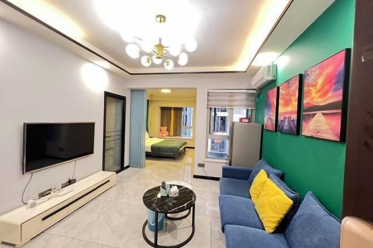 Ein modernes Wohnzimmer mit Flachbildfernseher, Couchtisch, Sofa und einer Deckenleuchte.