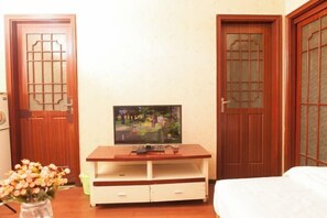 A room with a wooden TV stand, a bed, and two doors with traditional designs. - Chongqing Ruika Apartment (Guanyinqiao Pedestrian Street) (Chongqing)