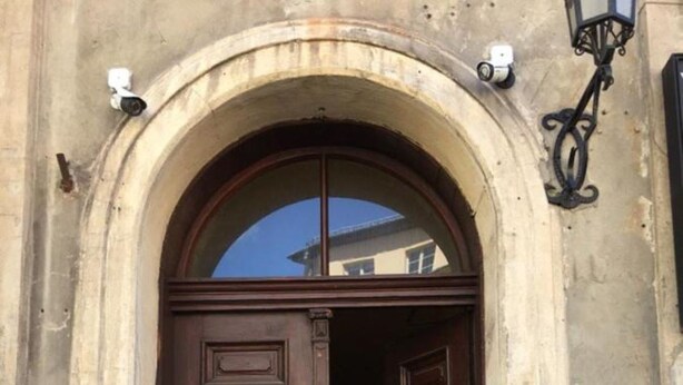 Una porta doble de fusta amb un rètol que diu "APJUMI APARTMENTS" i un petit graó que hi mena.